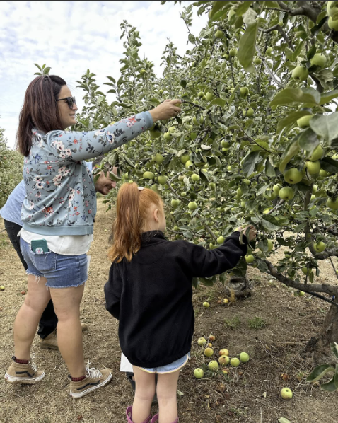 Mother and daughter picking apples from trellis