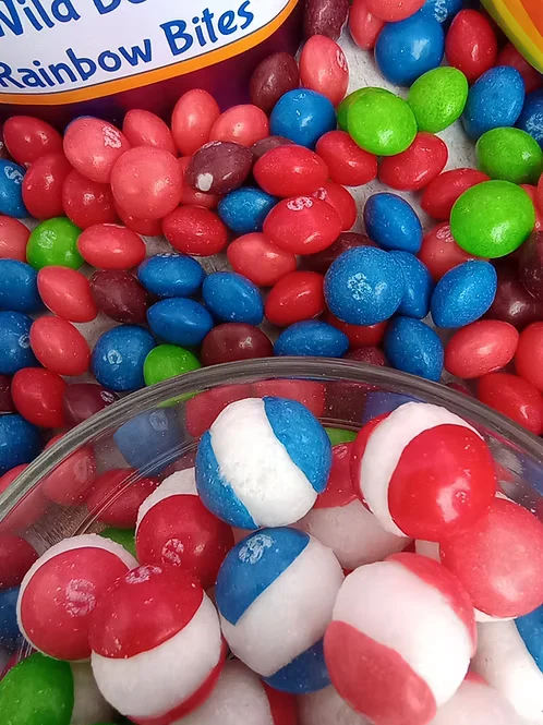Freeze-dried Rainbow Bites candy in bright reds, blues and greens, with a bowl of red, white and blue pieces in front.