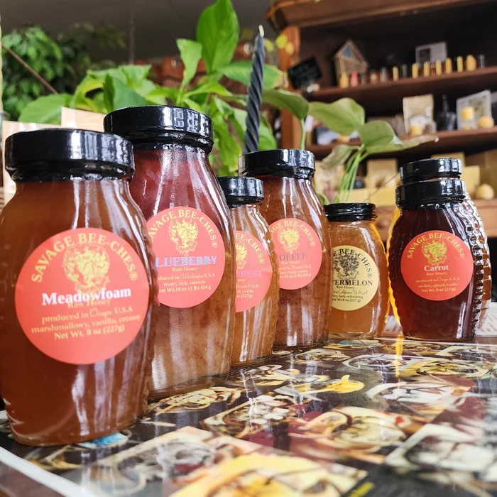 A row of Savage Bee'ches raw honey jars with red labels, including Meadowfoam, Blueberry and Carrot.